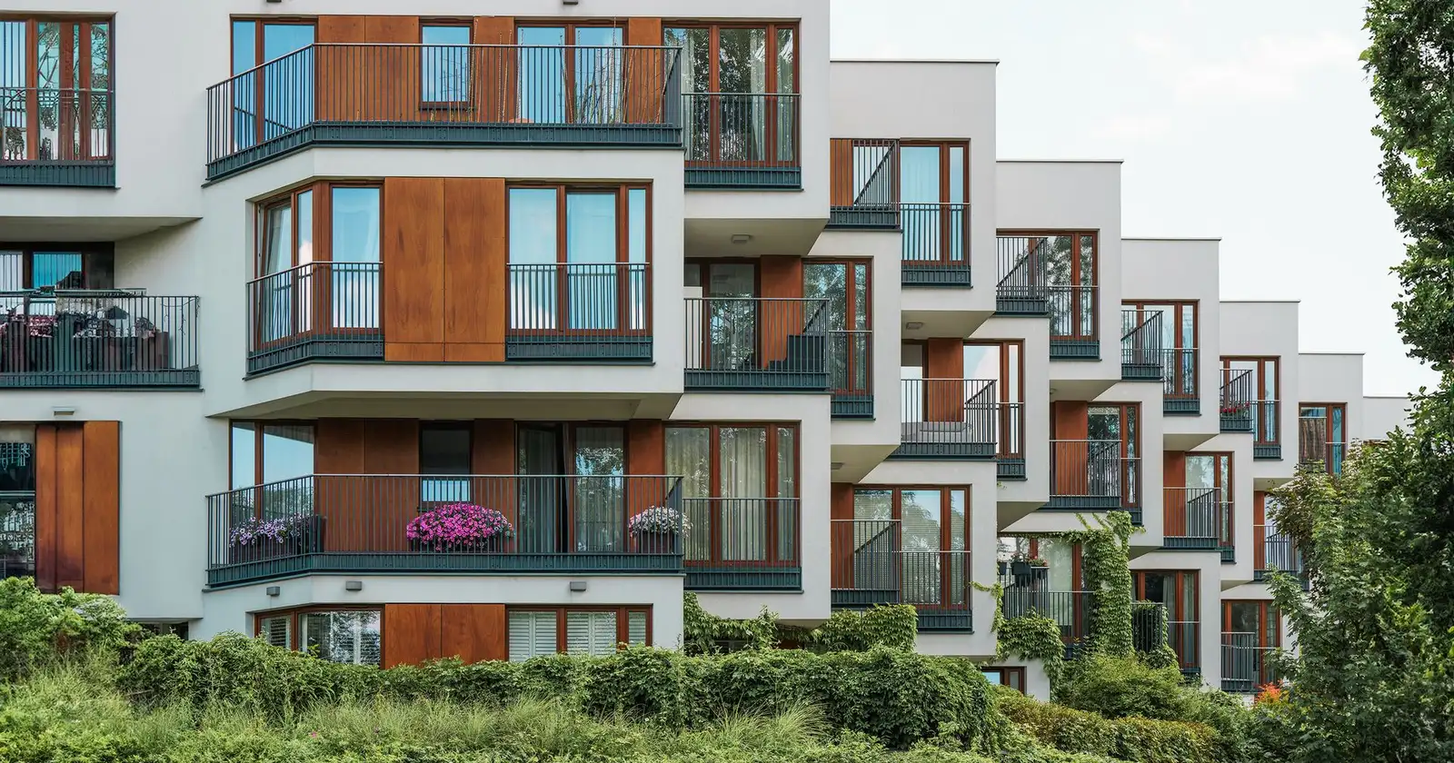 Immeuble de logements collectifs récent avec balcons, entouré de végétation